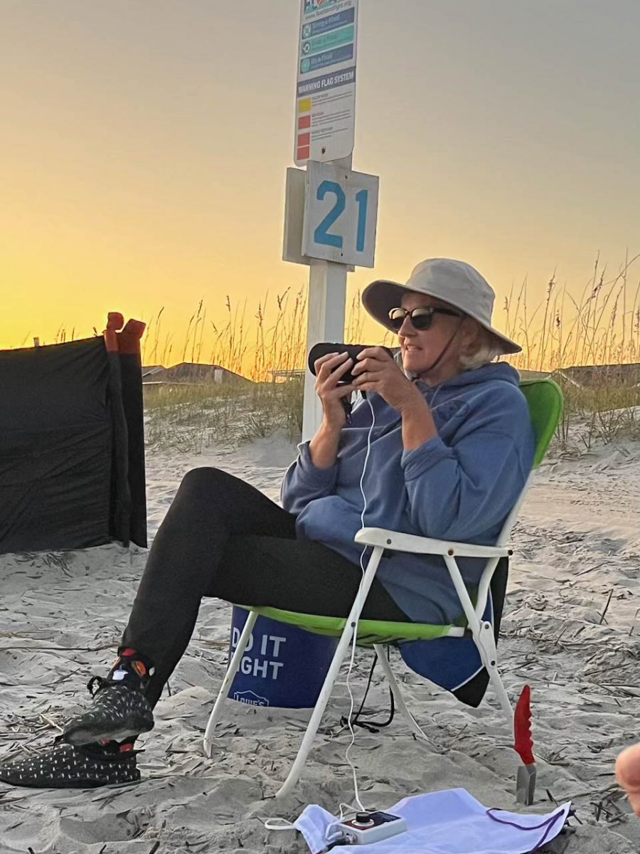 A sea turtle volunteer listens to the sea turtle hatchling sounds through a bluetooth speaker connected to a hydrophone.