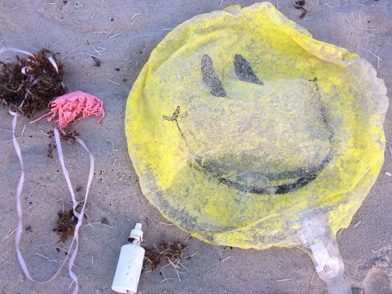 Ballon, string, and trash on a beach.